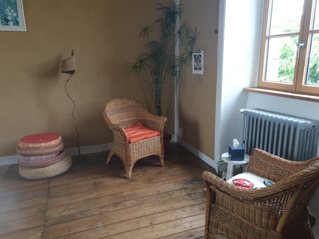 Photo de deux fauteuils face à face en rotin dans le cabinet, grande fenêtre sur la droite